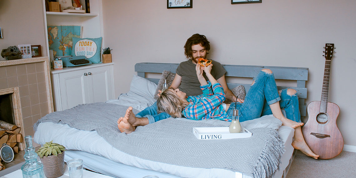 couple in bed eating pizza