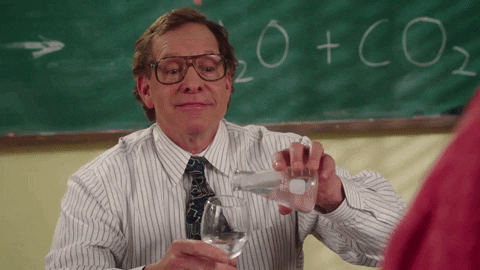teacher pouring liquid from beaker into wine glass