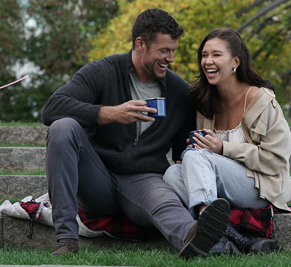 Bachelor Clayton and Gabby are sitting, laughing, with a picnic basket