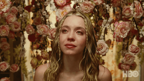 Sydney Sweeney as Cassie in Euphoria sitting in front of floral background, crying