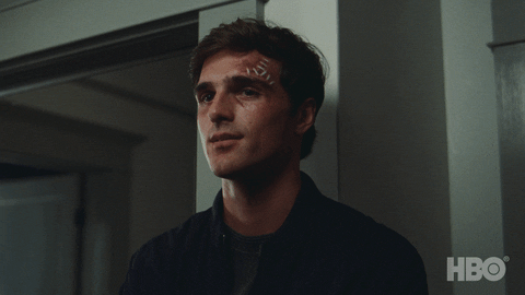 Jacob Elordi as Nate in Euphoria smiles to himself with visible injuries and bandages on his forehead
