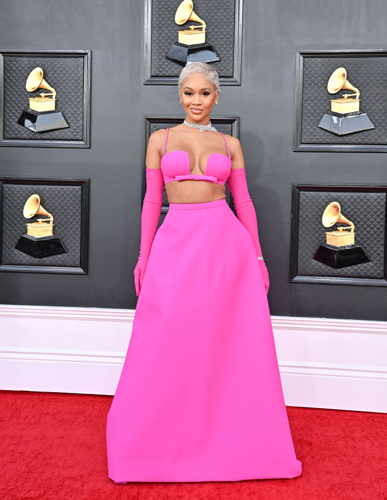 Saweetie at the 2022 Grammys red carpet in a pink two-piece crop top and skirt set with matching gloves