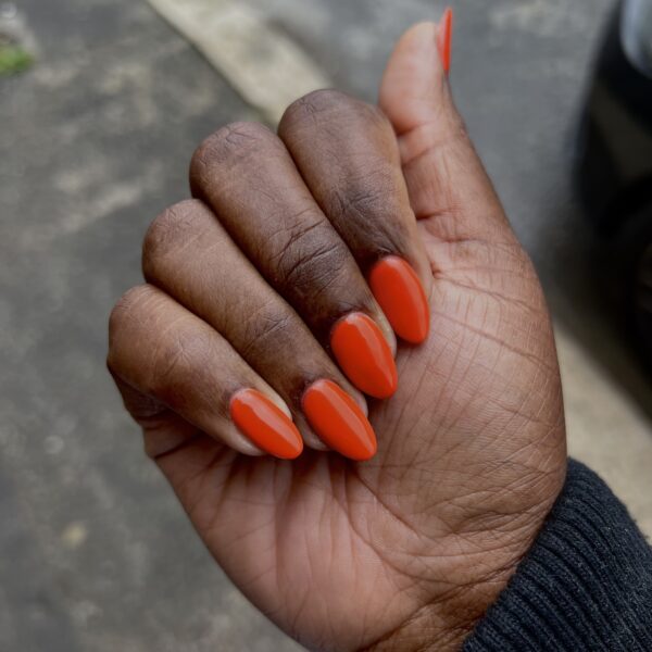 A woman showing off her burnt orange manicure.