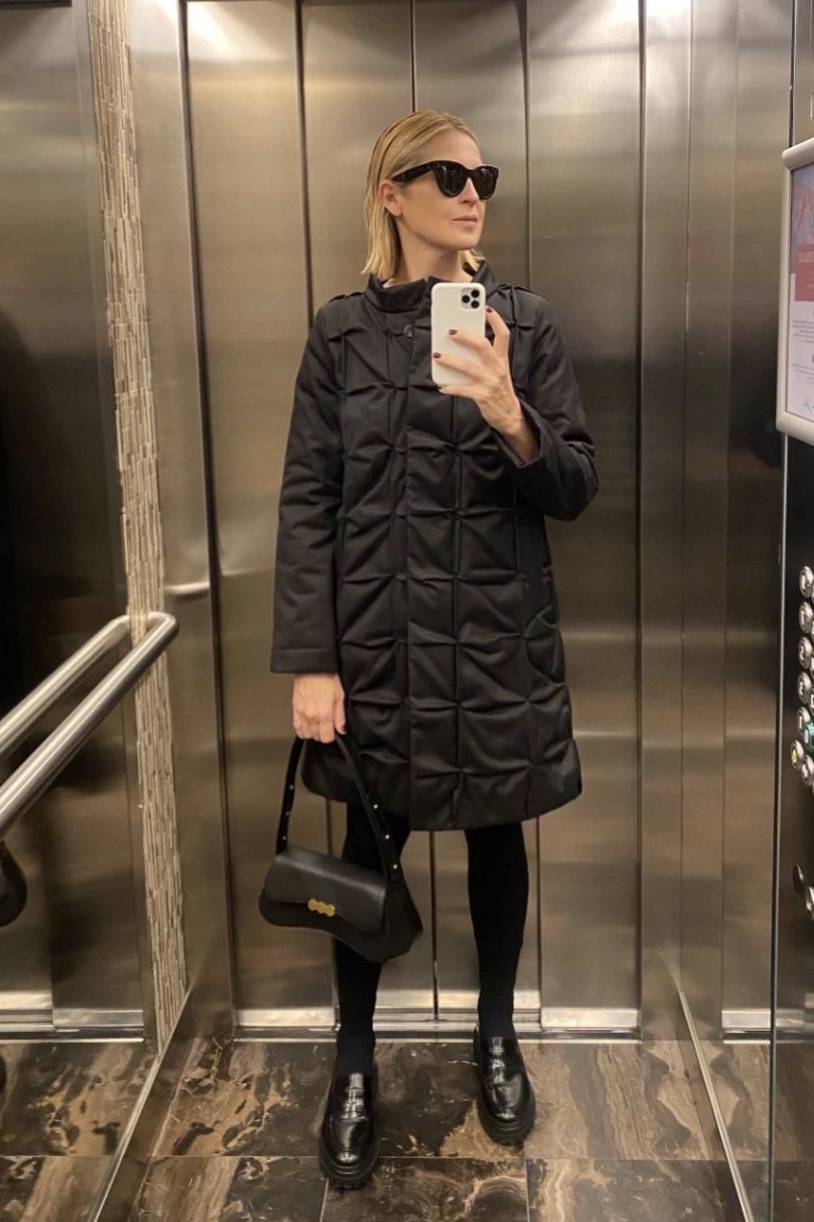 Kelly Rutherford wearing a black puffer while taking a mirror selfie in an elevator