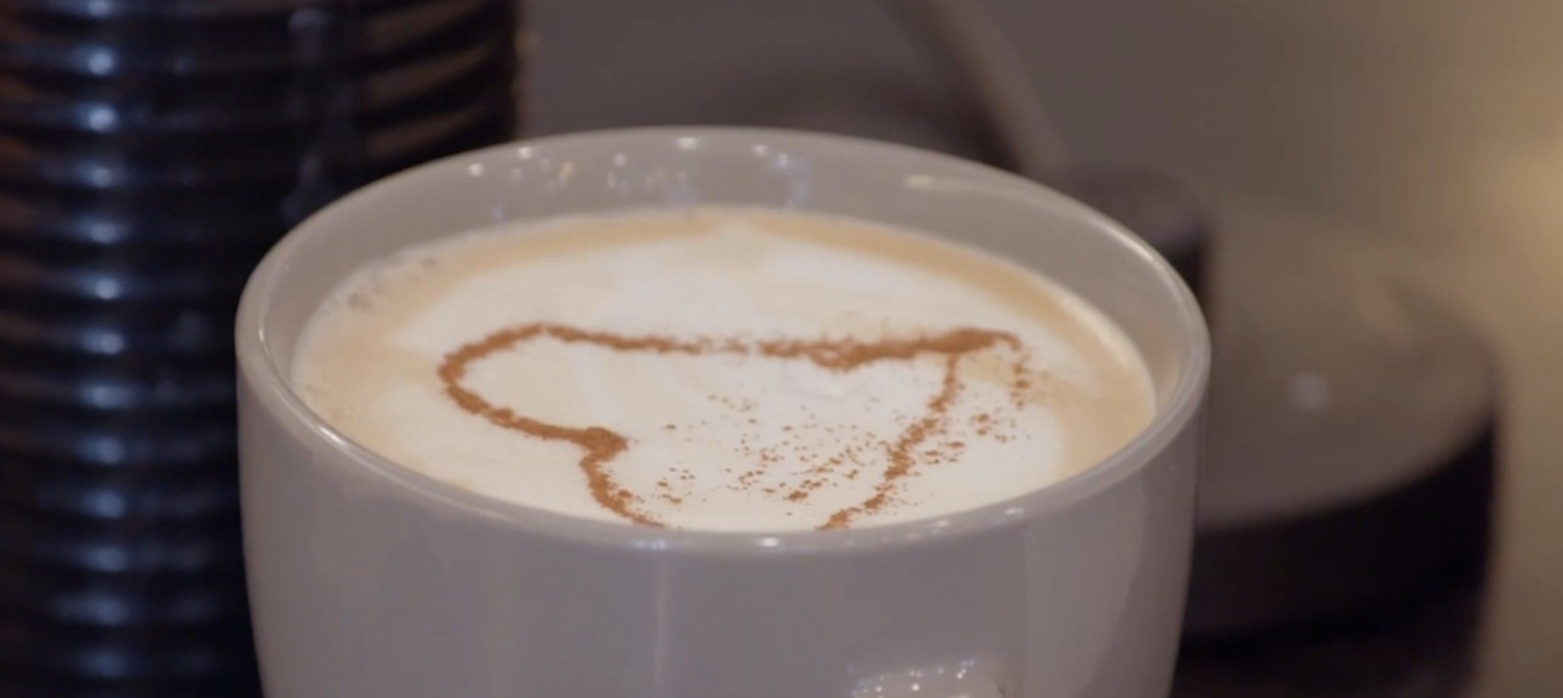 A close up of a mug filled with a latte with a cinnamon heart on top