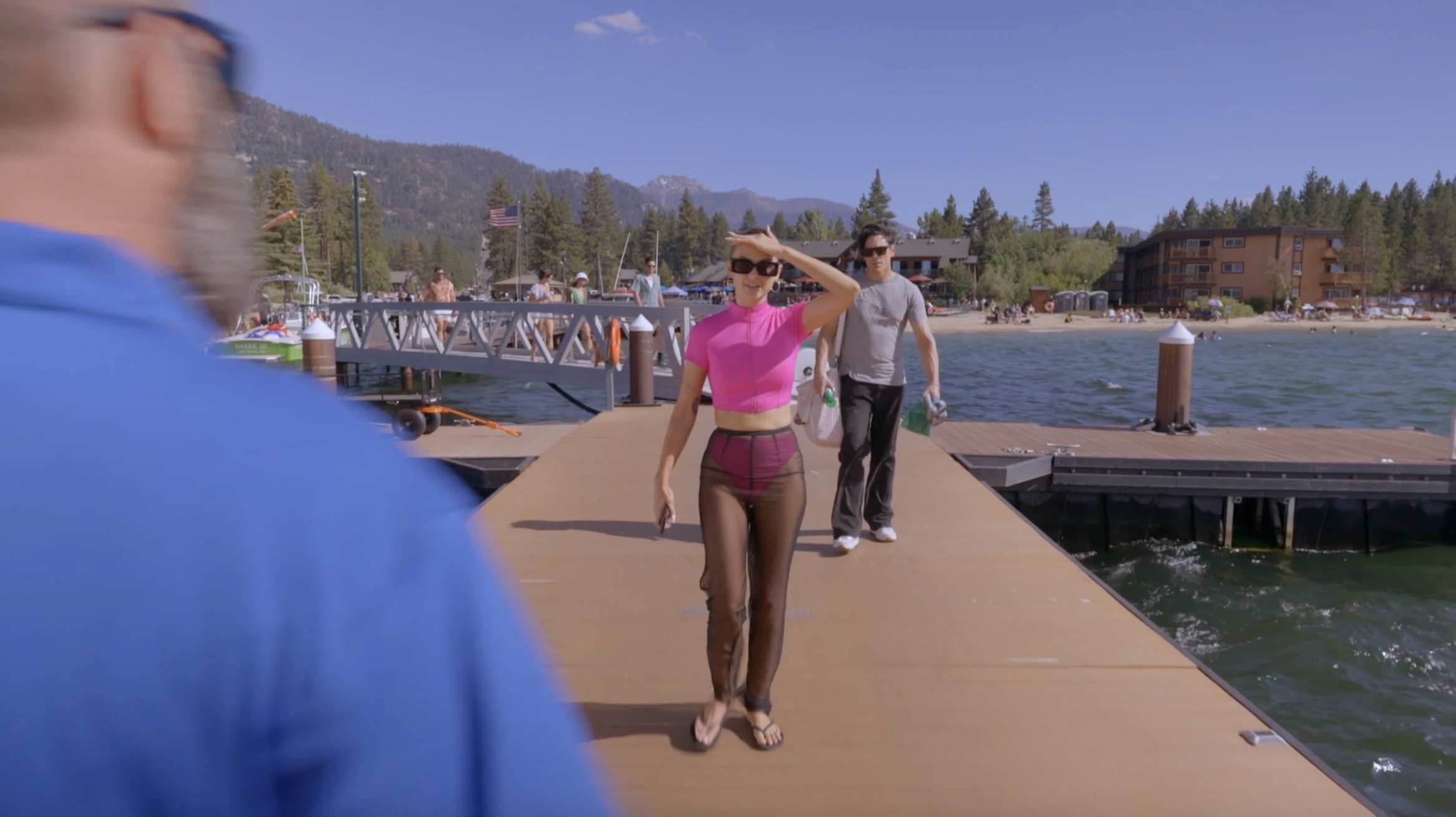 Lala walking down a boardwalk in a pink zip up swim top