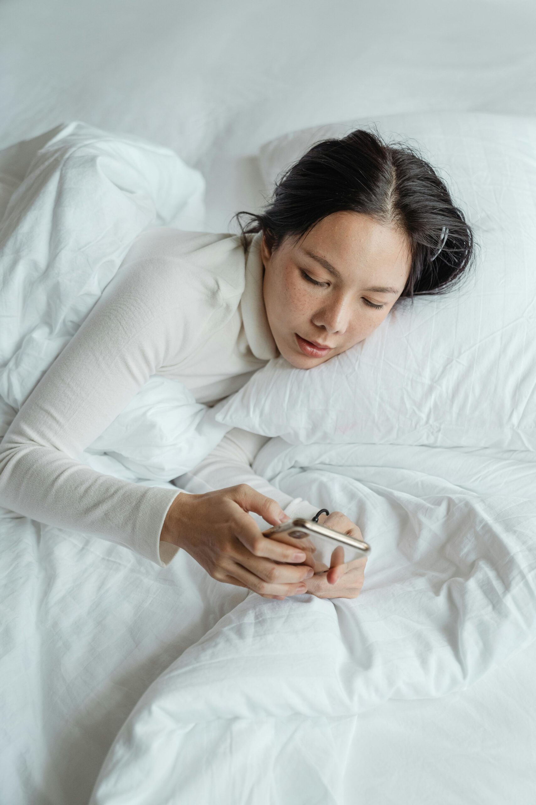 woman in bed on her phone